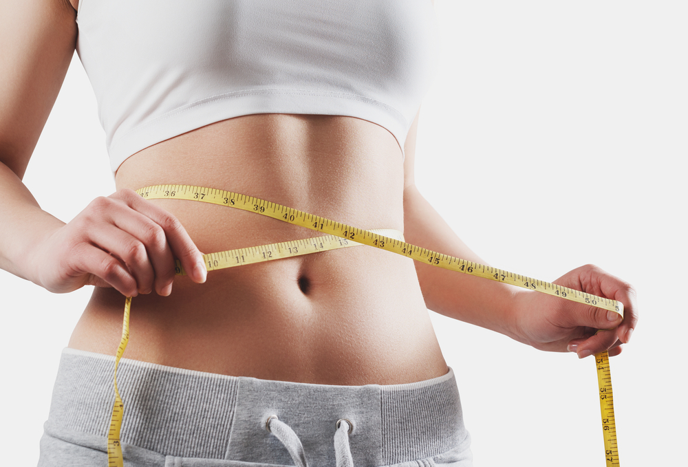 View of a woman's midsection as she measures around her waist